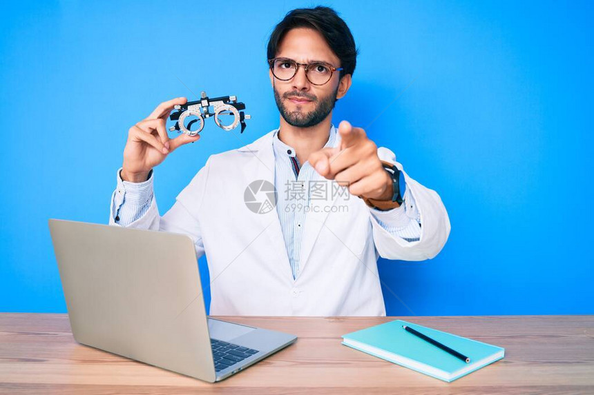 诊所里帅气的有眼观光师男子拿着几何镜像眼镜用手指对着摄影机和你自信的手势图片