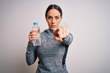 身穿运动服的年轻健身女从塑料瓶中喝水背景图片