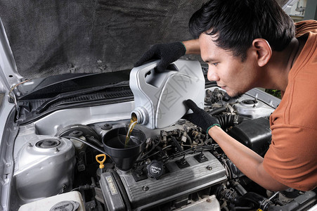 泰国技工将新鲜发动机油倒向旧车发动机图片