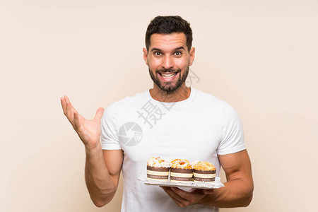 长得帅的男人拿着松饼蛋糕在孤立的背景和面部表图片