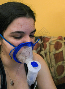 年轻女在家教练家用吸入器面具吸入气喘治疗图片