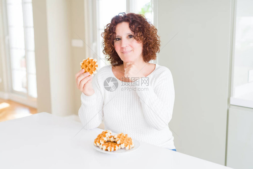 老年女人吃甜的贝吉安华夫饼面对严肃的面孔想着问题图片