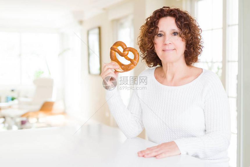 高龄女人吃德国咸的糕饼脆面盘以自信地表现在聪明的面孔图片