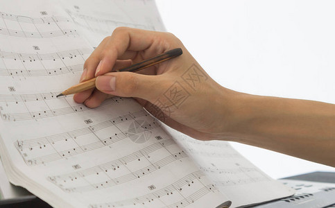钢琴演奏家手中的手正在用老笔在钢琴工作人员或工作表图片