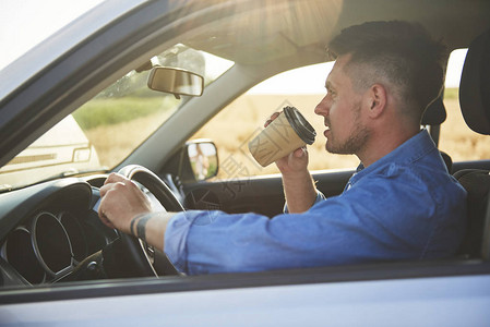 年轻人开车匆忙喝咖啡图片
