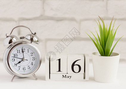 5月16日在木制日历上每月的天日历和闹钟在浅色背景上院子里的春天背景图片