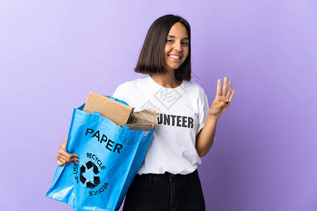 年轻拉廷女人拿着一个回收袋满纸的废纸来回收被隔离在紫色快乐和图片