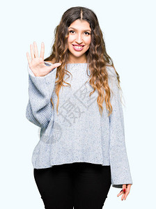 身穿冬毛衣的年轻美女带着五指举起手指满怀自信和快乐图片