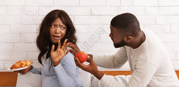 黑人男子乞求其怀孕妻子吃水果妇女持有羊角面包孕期食图片
