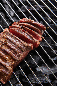 切新鲜烤熟的美味牛排和稀有烤肉在黑煤图片
