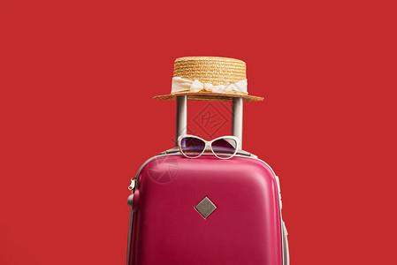 红色彩旅行袋上面有草帽和墨镜背景图片