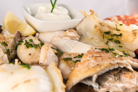 一份烤鱼盘子的详情上面装有白鱼虾鳕鱼背景图片