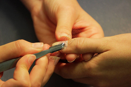修指甲培训课程的学生先为一位女客户的手准备用刮刀的工具背景图片