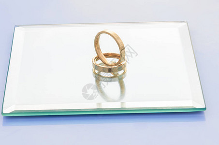两个奢华金环的紧闭完美的订婚戒指在白色背景的玻璃板上图片