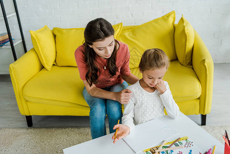 坐在黄色沙发上看客厅画像的孩子旁边的小孩旁图片