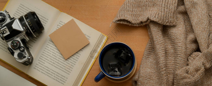 用咖啡杯毛衣开书笔记板和木制桌子照相机背景图片