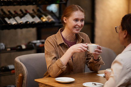 微笑的年轻女子在咖啡馆与朋友见面时图片