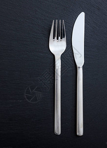 餐桌设置商务午餐黑背景的叉子和刀头图片