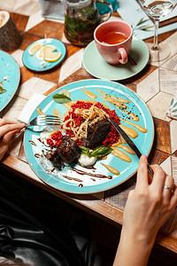 一个女孩在餐馆里用叉子和刀子吃肉饭图片