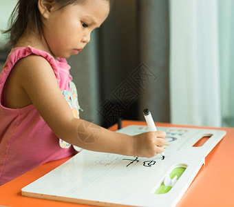 在家里用书和铅笔写手语协调技能的年幼儿童图片