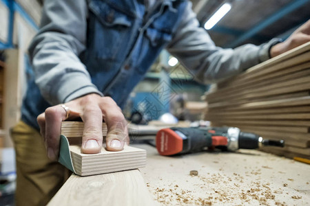 由砂纸制成的木材研磨过程对木匠与木板一背景图片