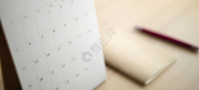 用笔和记本结束木制表背景的日历页商业规划任命概图片
