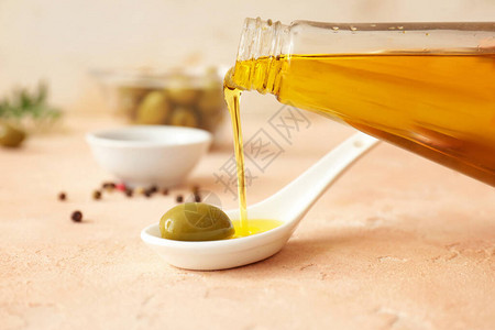用勺子把橄榄油倒在桌子上图片