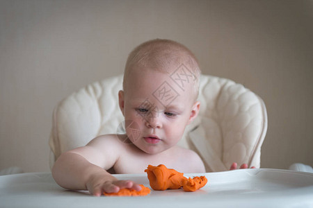 孩子们的创造力婴儿试图用橙粘土雕塑可爱的小男孩从桌上的塑背景图片