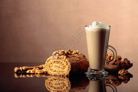胡桃蛋糕和含奶油的咖啡拿铁在反射背景图片