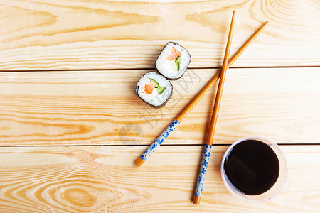 木桌上的寿司卷筷子和酱油顶视图图片