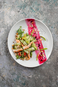 白盘上的蔬菜虾和切坚果沙拉图片
