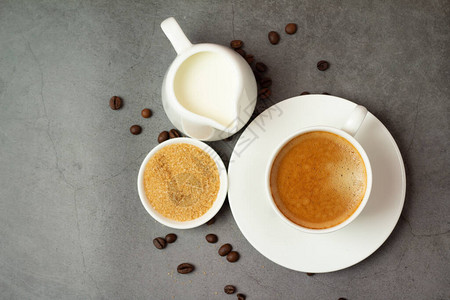 黑咖啡在白杯中牛奶和棕色糖在黑图片