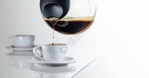 玻璃桌上的陶瓷杯中的黑咖啡咖啡从咖啡机倒进杯子图片