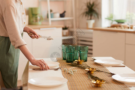 年轻女子在最起码的厨房室内复制空间供餐桌服务时的温暖图片