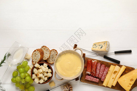 奶酪火锅配白色木质背景的小吃图片
