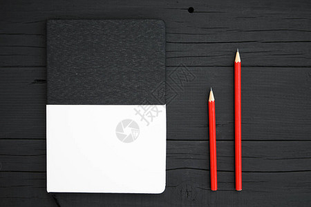 空白笔记本和铅笔黑木桌上的红铅笔和空背景图片
