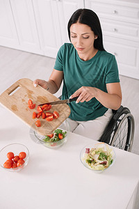 残疾青年妇女坐在厨房桌旁轮椅上时在碗里图片