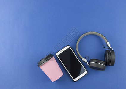 蓝色背景的耳机智能手机和纸杯咖啡的顶部视图有复制空间的耳机图片