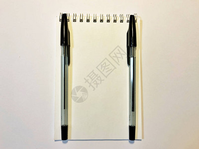 在白色木桌上打开带空白页和笔的记本图片