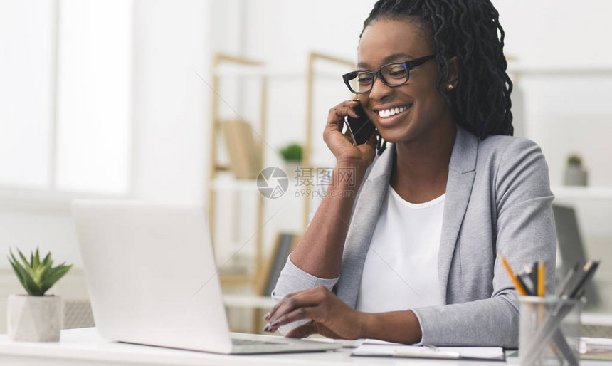公司通信黑人商业妇女谈论现代办公室在笔记本电脑上操作移动电话的问题图片