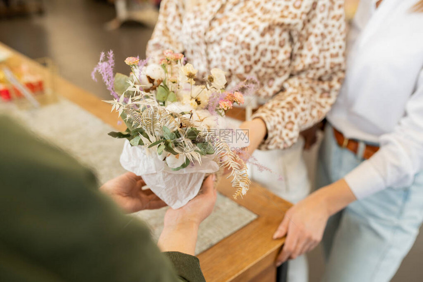 花店年轻老板的手拿着一束花朵在柜台上图片