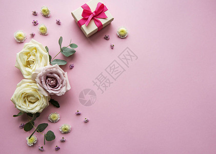 亮粉红背景的礼品盒和各种彩色花朵平面顶视图图片