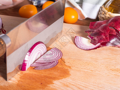 用大刀切红洋葱在厨房切削板上半个圆环的切成剪切图片