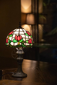 旧灯深色模糊背景上带有彩色玻璃灯罩特写的古董台灯带有花卉图案的发光马赛克灯由闪亮的彩色玻璃片制成的背景图片