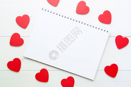 红色的心形纹理与爱和木制白色背景上的笔记本图片