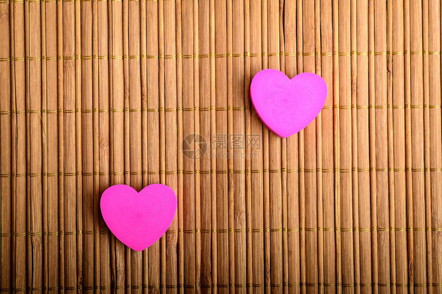 两颗粉红心在棕竹桌装饰上顶视或平坦有图片