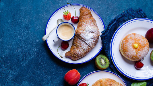 意大利早餐与羊角面包油炸饼咖啡和蓝图片