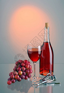 杯子和酒瓶加红酒红葡萄刷子和有反光的彩色背景金属软木箱反图片