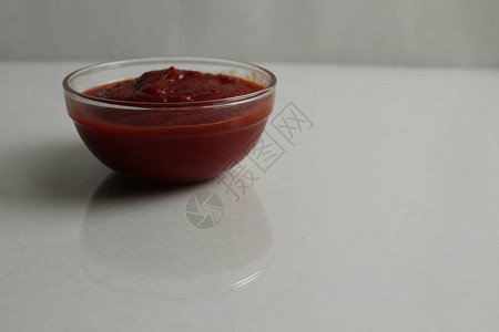 红番茄热辣或糖酱倒在一个玻璃酱锅碗盘上图片