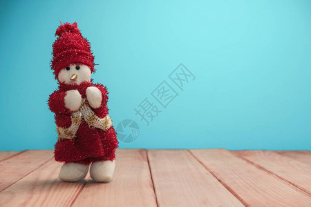 美丽的圣诞小玩意雪人穿着红色木桌和蓝色背景图片